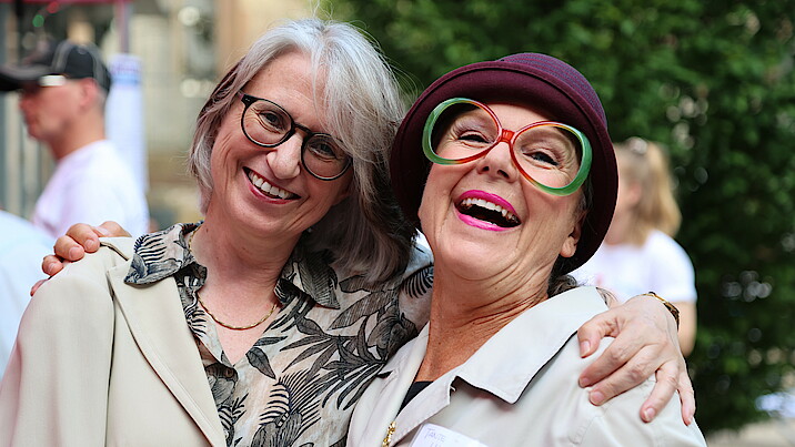 Vorstandsvorsitzende Dr. Annette Noller (l.) mit Kabarettistin Sabine Schief alias "Hildegard" lachen in die Kamera.