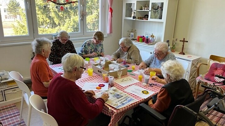 Sieben Seniorinnen sitzen an einem Tisch und basteln.
