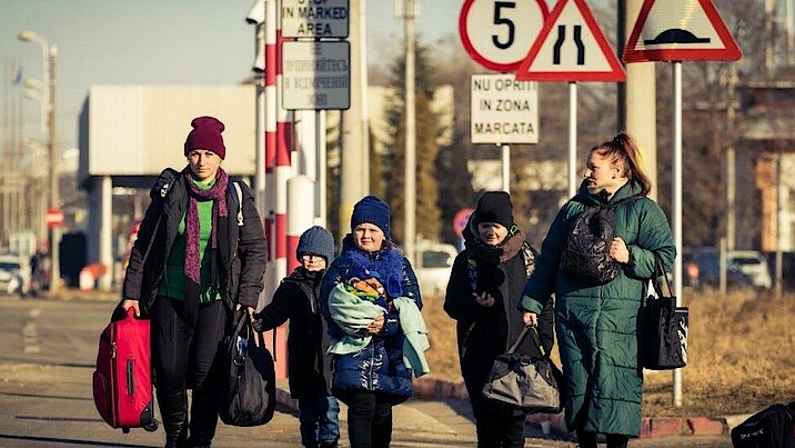 Zwei Frauen und drei Kinder sind auf der Flucht weg aus der Ukraine. Sie tragen Gepäck und sind den kalten Temperaturen entsprechend angezogen.