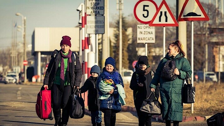 Zwei Frauen und drei Kinder sind auf der Flucht weg aus der Ukraine. Sie tragen Gepäck und sind den kalten Temperaturen entsprechend angezogen.