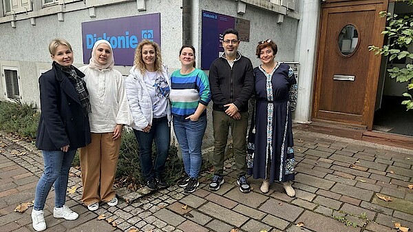 Mitarbeitende des Nadia Murad-Diakoniezentrum in Lörrach stehen vor dem Eingang und lachen.